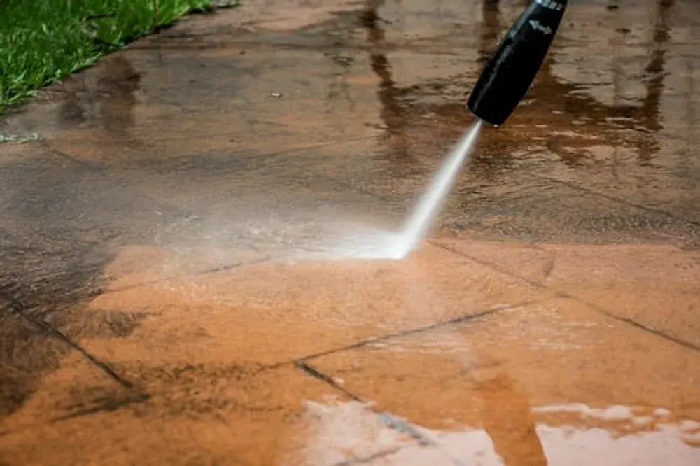 Pressure washer cleaning a stamped concrete patio surface