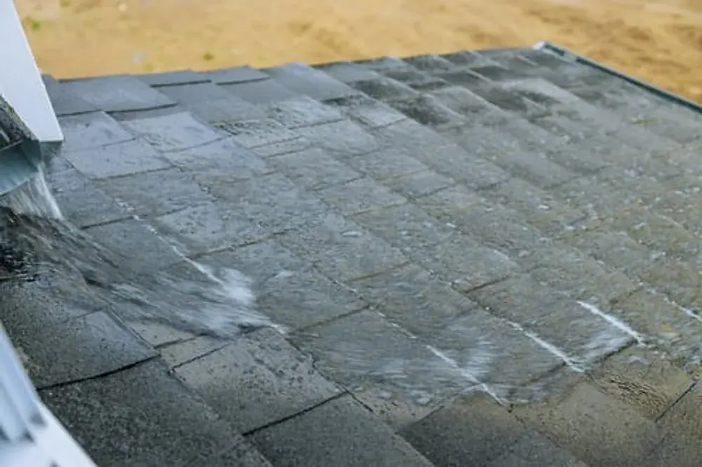 Meltwater running off an asphalt shingle roof after a winter freeze