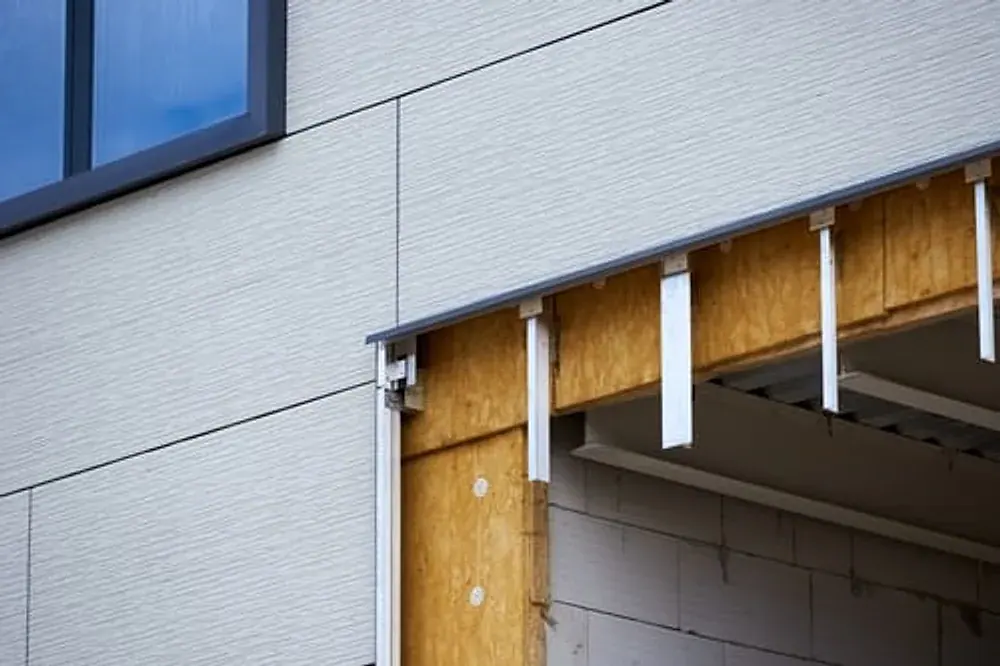 Exterior wall with siding panels removed exposing sheathing beneath