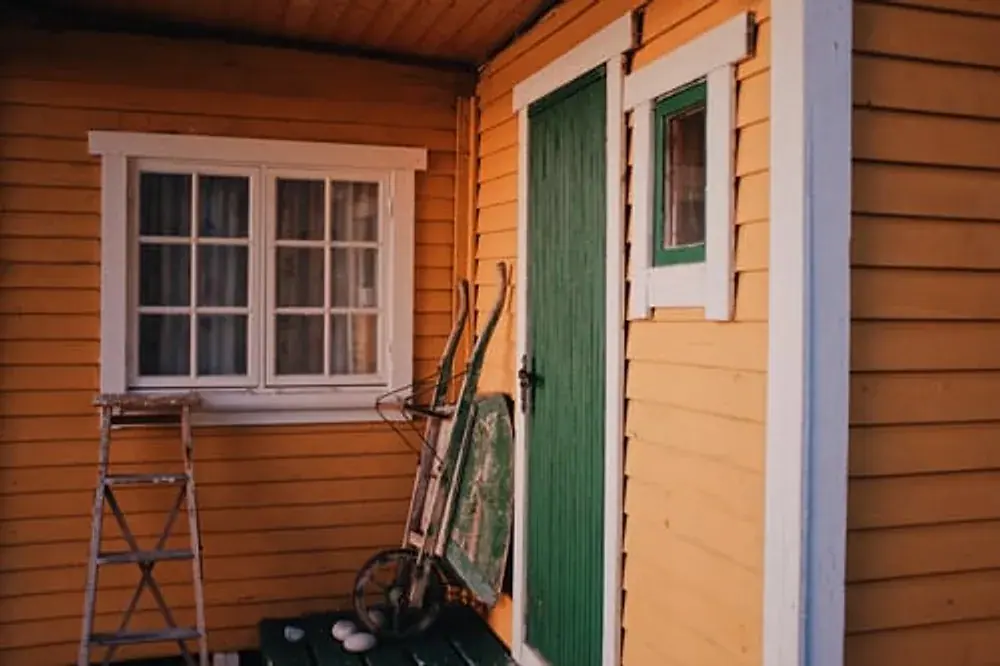 Wood clapboard house exterior mid-repaint with ladder in place