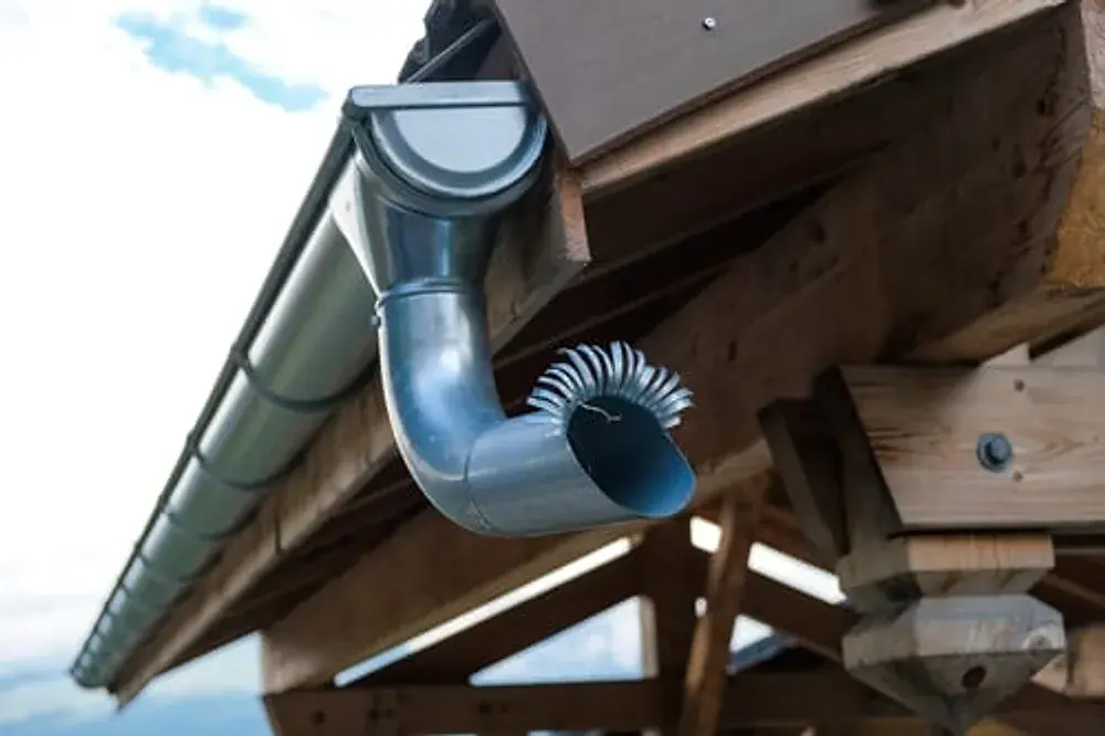 Downspout elbow and gutter section being repaired on a home exterior