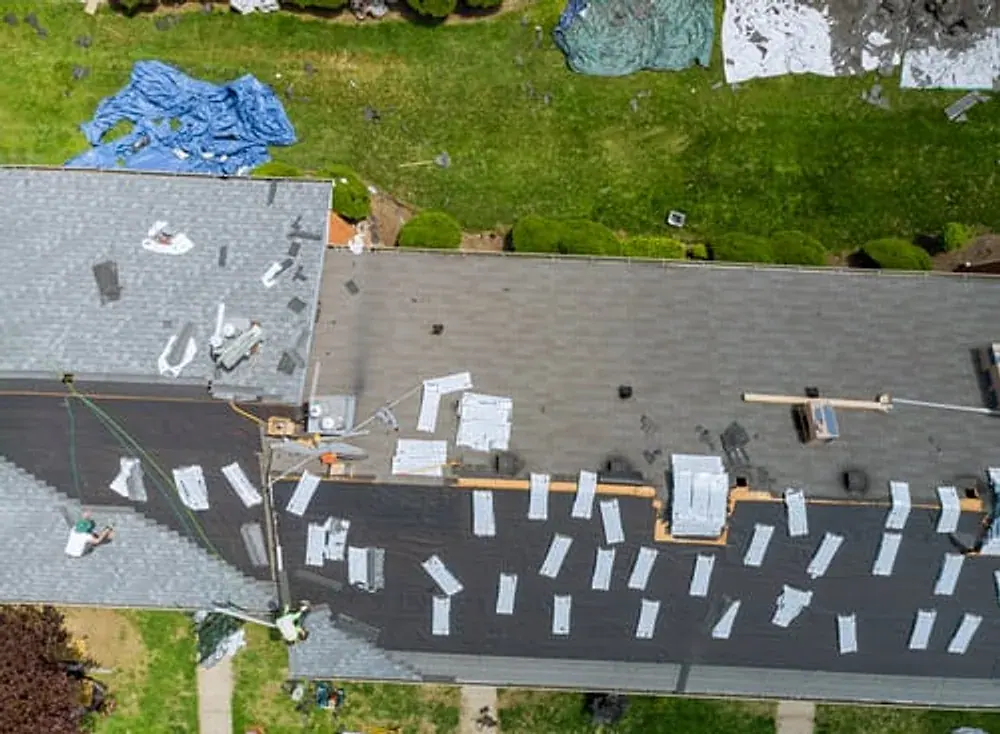 Crew installing a new asphalt shingle roof during a full roof replacement
