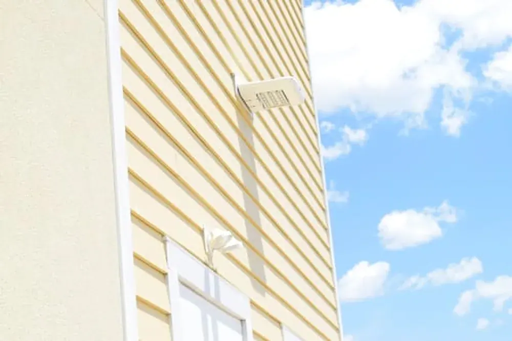 Newly installed light vinyl siding on a home exterior under blue sky